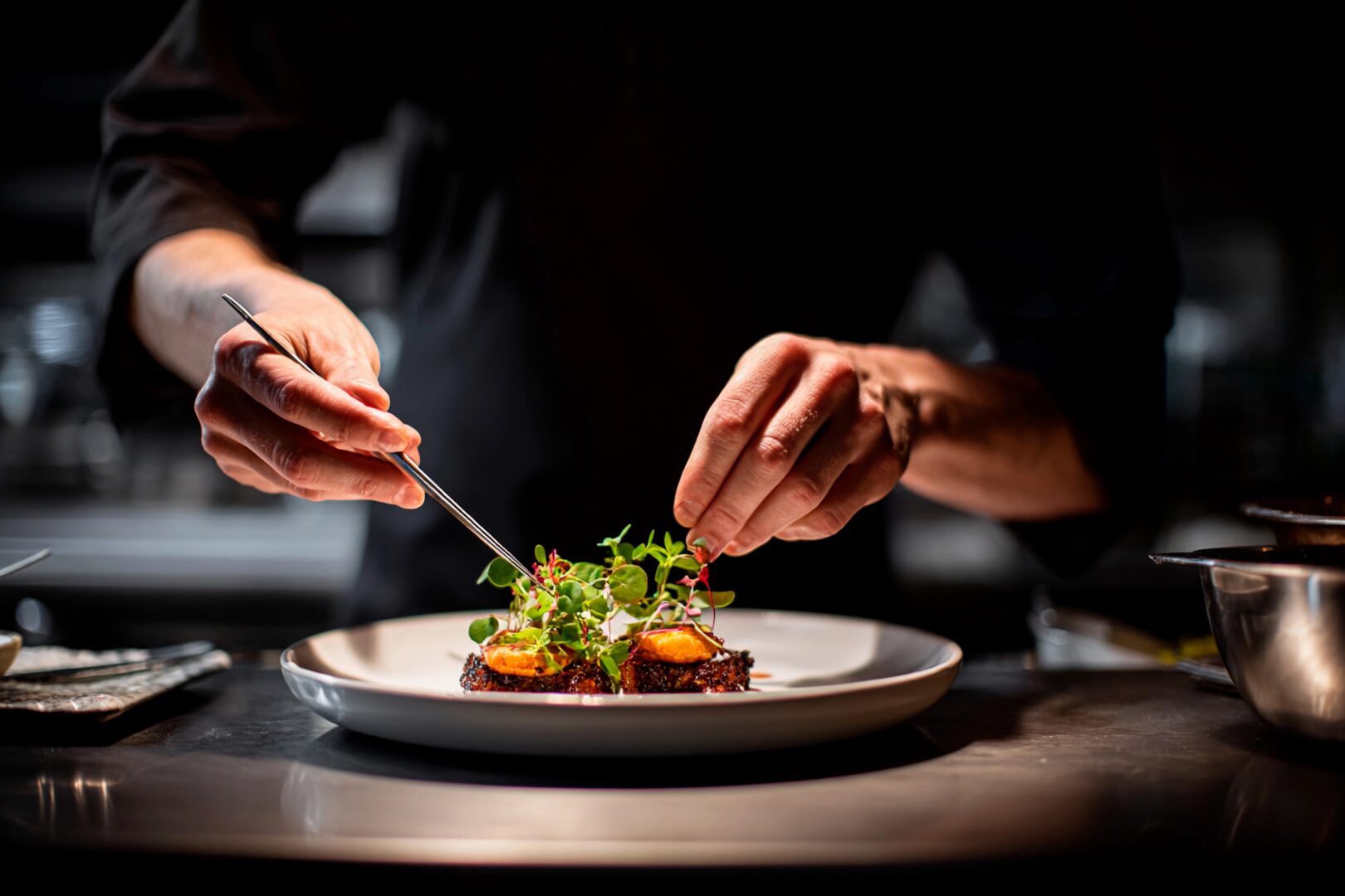 culinary travel tours: In a chic kitchen, a focused chef delicately garnishes a plated dish with fresh herbs and microgreens, showcasing culinary artistry during evening dinner preparation