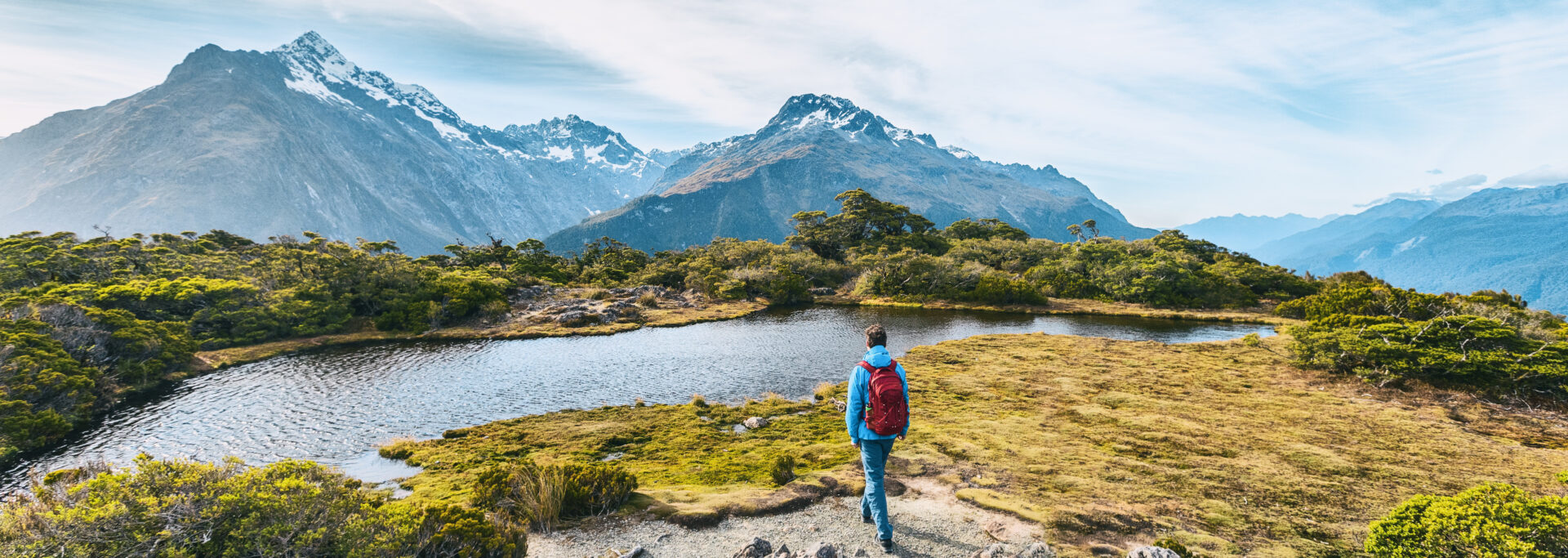 Hiking Vacations: Young hiking man walking on trail at Routeburn Track in Fiordland National Park in New Zealand.
