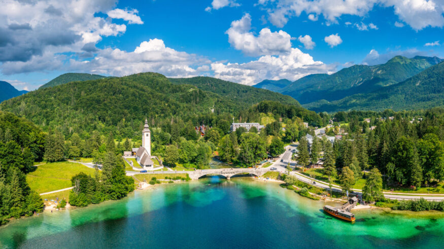 Aerial view of Bohinj lake in Julian Alps. Popular touristic destination in Slovenia. Bohinj Lake, Church of St John the Baptist. Triglav National Park, Julian Alps, Slovenia.