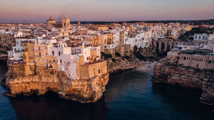 An aerial view of a sunset sky over the skyline of Polignano a Mare, Puglia, Italy