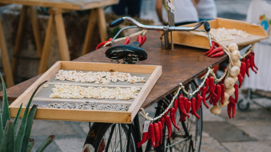 Fresh orecchiette or orecchietta, made with durum wheat and water, drying on a wooden board on a bike with red chili and garlic, handmade pasta typical of Puglia or Apulia, a region of Southern Italy