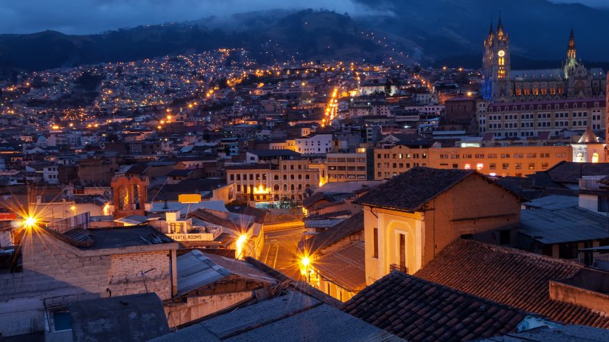 Quito, Ecuador old town and basilica at night with mountains in the background